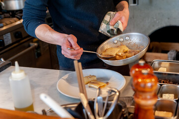 厨房での調理シーン　料理を盛り付けるシェフの手元　