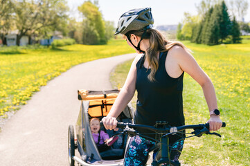 Naklejka premium woman riding a bicycle with a baby stroller attached to the bicycle.