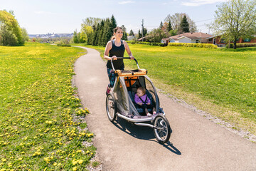 Beautiful young family with baby in jogging stroller running outside in summer season
