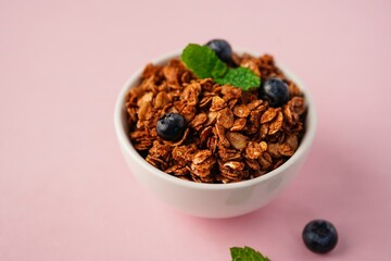 Homemade Chocolate cocoa Granola  bowl isolated on light pink background- healthy breakfast concept, selective focus