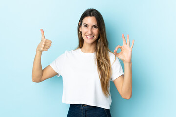 Young caucasian woman over isolated background showing ok sign and thumb up gesture