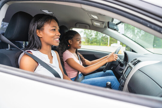 Young Black Teenage Driver Seated In Her New Car With Her Mother