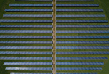 Solar panels on a green lawn aerial view. The road between solar panels on the grass, top view.