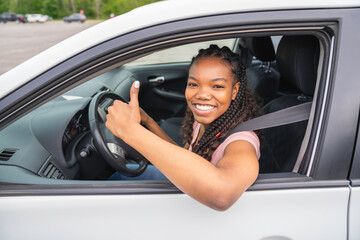 Young black teenage driver seated in her new car