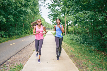 Obraz premium Mother and teen daughter running in green park in summer time