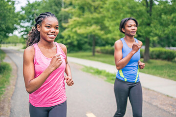 Fototapeta premium Mother and teen daughter running in green park in summer time