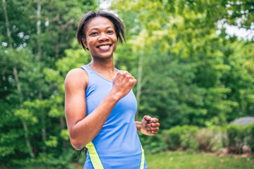 Woman runner in action outside in tree background