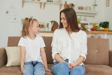 Obraz premium The trusting relationship of mom and daughter. Conversation of a woman with a little girl at home on the couch in the kitchen. Best friends happy motherhood weekend together with kid concept