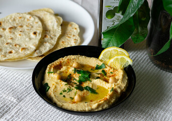A bowl of homemade Hummus. Hummus with flat bread, olive oil, lemon and parsley. Copy space. Vegan food
