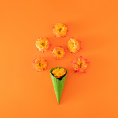 fresh orange and yellow roses with green ice cream cone on the summer bright orange background. tropical abstract art. minimal flat lay background