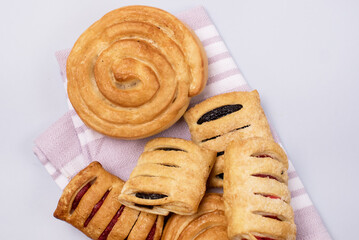 Variety of Homemade Puff Pastry Buns Sweet Rolls Buns with Jam on Linen Napkin Blue Background Top View
