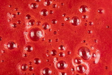 Strawberry smoothie texture. Abstract red background with air bubbles.Red background, close-up, top view.