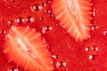 Food background. Strawberry slices in a strawberry smoothie. Red background, close-up, top view.