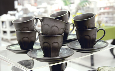 Black cups for tea on a glass table top.