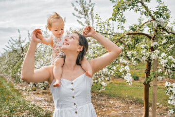 Obraz premium portrait of mother and baby girl outdoors in apple tree flower