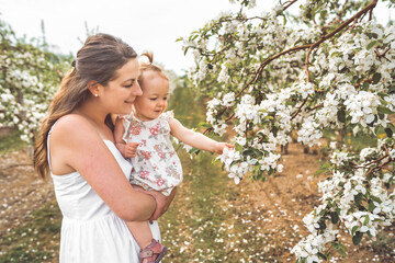 portrait of mother and baby girl outdoors in apple tree flower