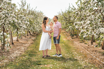 Fototapeta premium portrait of family and baby girl outdoors in apple tree flower