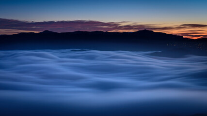 Creu de Sant Miquel Vewpoint, in Montserrat, at night, with a night sea of clouds - fog (Barcelona, Catalonia, Spain)