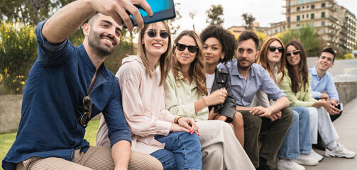 Multiracial young schoolmates having fun outdoors taking selfies. Young people hangout together using tech
