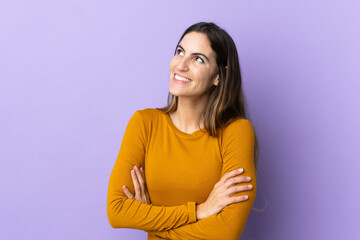 Obraz premium Young caucasian woman over isolated background looking up while smiling