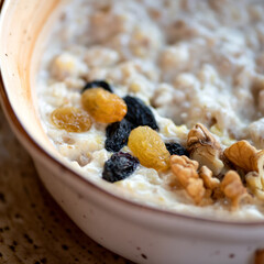Close up of Cereal oatmeal or porridge with milk, raisins and nuts. Traditional english breakfast. Soft focus.