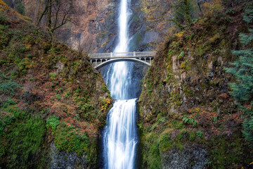 View of a bridge going over a river with Multnomah Falls in the background. Colorful Art Render....