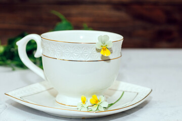 A beautiful white cup with a gold border decorated with flowers. Business account design.