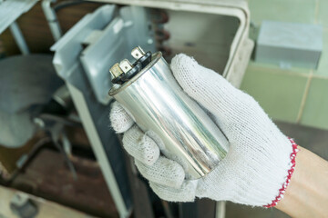 Technician hand with air conditioner capacitor, Checking air compressor capacitor, Home appliances repair service.