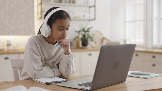 Muslim kid in headphones and having zoom call on laptop