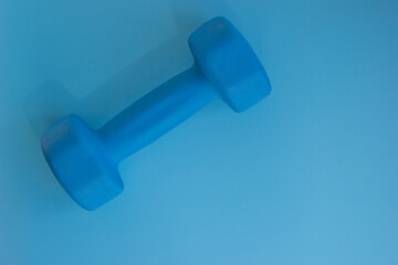 Blue dumbbells for home sports. Lie on a blue background, close-up.
