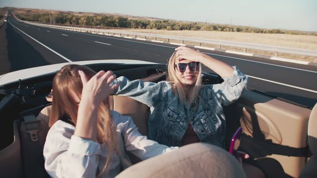 Group of friends driving off road convertible car during roadtrip - Happy travel people having fun in vacation - Friendship, transportation and youth lifestyle holidays concept. Two women on the back