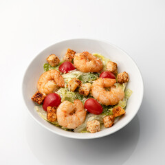 Spicy oriental seafood. Cooked shrimp or prawn mixed with vegetables, croutons and Cherry tomatoes. Pan-Asian cuisine. Food plate isolated on white background.