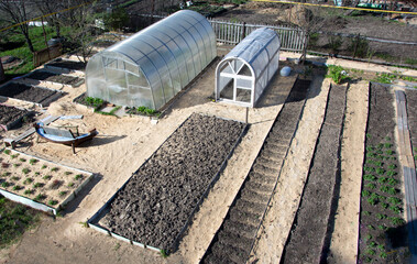 Vegetable garden top view. The landscape of the garden area. Smooth long beds and greenhouses.