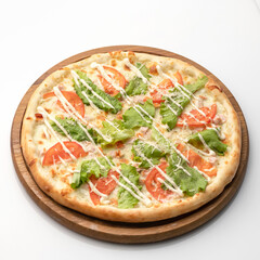 Whole vegetarian pizza isolated on white background. Hot pizza with melted cheese, lettuce and tomatoes on round wooden cutting board. Fast food concept. Healthy eating.