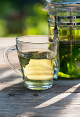 A cup of mint tea on a wooden table in the summer garden	
