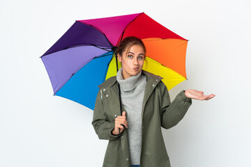 Young woman holding an umbrella isolated on white background having doubts while raising hands