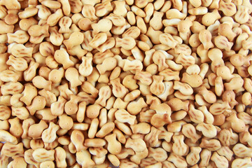 The background of a delicious cookie-cracker in the form of many small fish. The concept of pastry shops, cookeries, cafes, grocery stores, baby food.