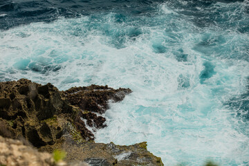 Sea foam wave running on a rocky shore top view, summer background