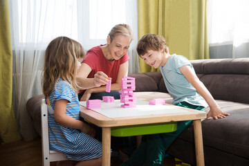 Mom and two kids playing  board game together at home.  Family having fun playing at home. Family board games. 