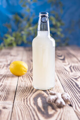 ginger beer bottle, lemon and ginger root on wooden background