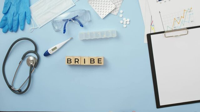 Doctor puts wooden cubes with the collected word bribe with hands. Concept of corruption in medicine.