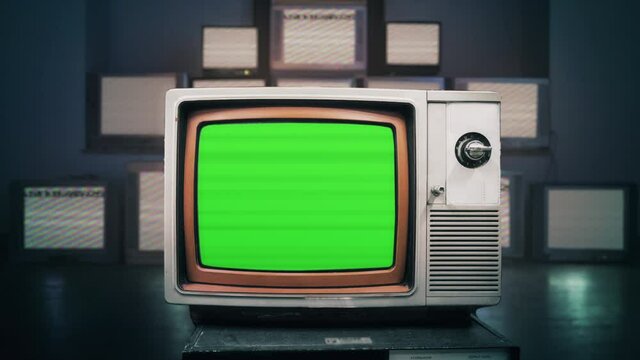 Green Screen Television Retro Technology Background TV Zoom In TV. Vintage television display a green screen, for replacement, with many broken monitors in the background.