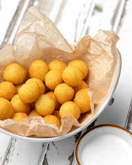 Delicious fried croquette balls in parchment paper. Light snack. Bowl of tasty rustic food on white...