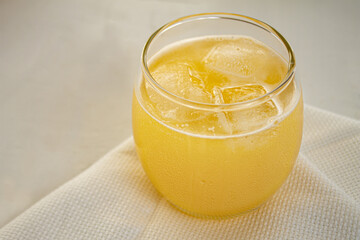 
glass of yellow juice in glass tumbler