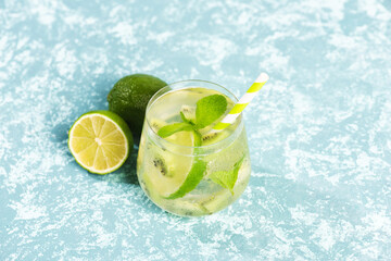 A glass of mojito cocktail with lime and mint and kiwi