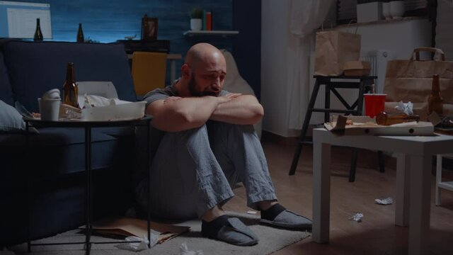 Mature traumatized stressed man going through episode of bipolar disorder when depression hits feeling of loneliness making to suffer crying in pain sitting on floor thinking of disappointment