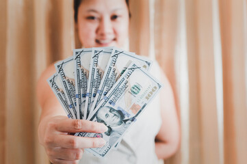 The right hand of a white woman holding a mock-up hundred-dollar money banknote for shopping. selective focus.