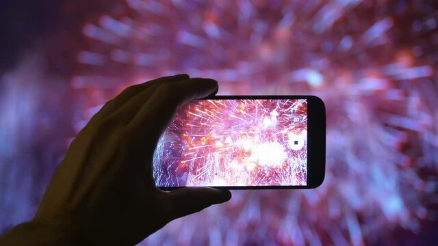 Person taking picture of the fireworks exploding show in 4K