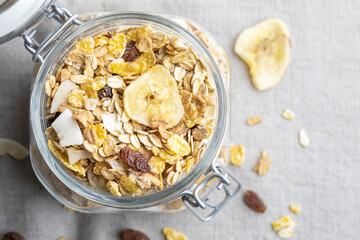 Glass jar with whole grains for breakfast. Muesli with dried fruits and dried fruits. With copy space. Top view.