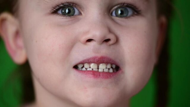 The girl shows her baby teeth, white baby teeth, oral hygiene, slow movement of the child.